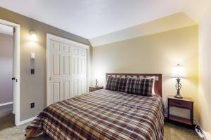 a bedroom with a bed with a plaid blanket and a door at Stateline Serenity in Stateline