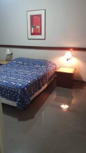 a bedroom with a bed and a table with a lamp at Plaza Flat C/ Serviço De Quarto in Ribeirão Preto