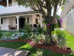 a garden in front of a house with a tree at Bela casa de praia, arborizada, um paraíso! in Salvador