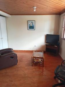 uma sala de estar com uma televisão e uma mesa em Casa Ecoturística, Disfruta de la Naturaleza , Avistamiento de Aves, Reserva Natural, Cascadas, Restaurantes Típicos , a una hora de Bogotá. em San Antonio