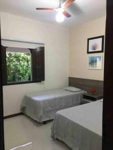 - une chambre avec 2 lits et un ventilateur de plafond dans l'établissement Bela casa de praia, arborizada, um paraíso!, à Salvador