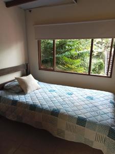 um quarto com uma cama e uma grande janela em Casa Ecoturística, Disfruta de la Naturaleza , Avistamiento de Aves, Reserva Natural, Cascadas, Restaurantes Típicos , a una hora de Bogotá. em San Antonio