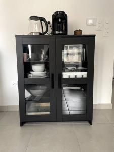 a black cabinet with dishes and a kettle on it at Charmant T2 à port Marianne in Montpellier