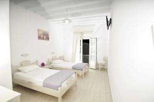 2 Betten in einem weißen Zimmer mit weißen Wänden in der Unterkunft Dimitra Pension in Mykonos Stadt