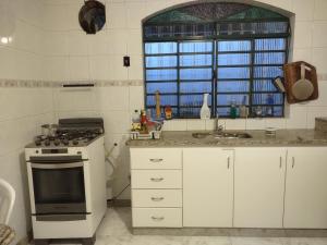 a kitchen with a stove and a sink and a window at Pousada Arvoredo in Contagem