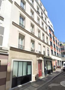 Loft 3 chambres Bastille, Marais, Père Lachaise في باريس: مبنى أبيض كبير بأبواب حمراء على شارع
