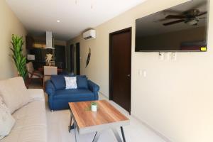 Departamento con terraza privada y alberca a 1 cuadra del Malecón - Flamingo 102 في مازاتلان: غرفة معيشة مع أريكة زرقاء وتلفزيون