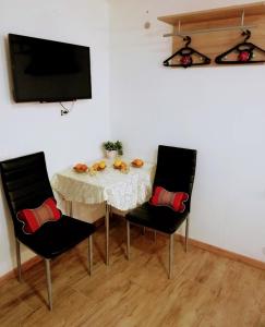 einem Esstisch mit 2 Stühlen und einem TV in der Unterkunft Apartma SunySun in Koper