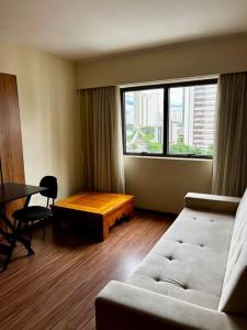 - un salon avec un canapé, une table et une fenêtre dans l'établissement Amazing Flat - Setor Oeste, à Goiânia