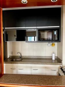 - une cuisine avec des placards blancs et un évier dans l'établissement Amazing Flat - Setor Oeste, à Goiânia