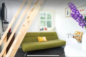 un sofá verde en una sala de estar con una escalera en Tiny house Watergang, en Watergang