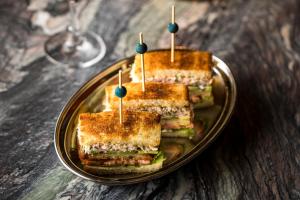 three sandwiches on a plate with a glass of wine at The Evelyn NoMad in New York
