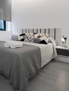 Habitación blanca con cama grande con almohadas en El Rincón de la estación en Ourense
