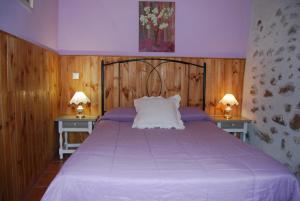 sypialnia z fioletowym łóżkiem z dwoma stołami w obiekcie Arroyo Milano Casa Rural w mieście Maello