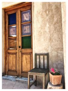 a wooden door and a chair in front of a building at Cabaña San Roque in Humahuaca