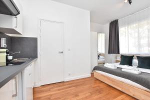 ein weißes Schlafzimmer mit einem Bett und einer Küche in der Unterkunft Beautiful Studio 2P CharonneFaidherbe in Paris