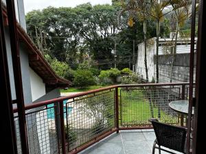 balcón con mesa y vistas al jardín en Village Hostel, en Petrópolis