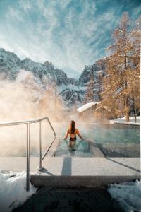 Una donna in una vasca idromassaggio nella neve di Kolfuschgerhof Mountain Resort a Colfosco