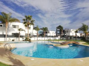 a large swimming pool with palm trees and buildings at Holiday Home in Residence KOMA in Torrevieja
