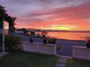 una casa con valla y vistas a la puesta de sol en Al Louise Accommodation, en Mangonui