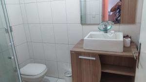 a bathroom with a sink and a toilet and a mirror at Apartamento praia do tombo Guarujá in Guarujá