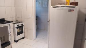 a white kitchen with a stove and a refrigerator at Apartamento praia do tombo Guarujá in Guarujá