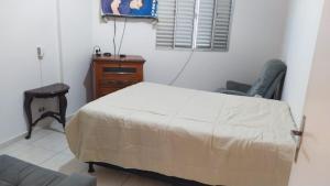 a bedroom with a bed and a chair and a window at Apartamento praia do tombo Guarujá in Guarujá