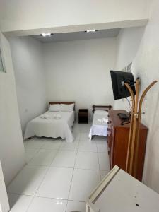 um pequeno quarto com 2 camas e uma televisão em Pousada El Camenito Geribá Búzios em Búzios