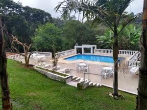 een zwembad met tafels en stoelen in een tuin bij Chacara Branca de Neve in Biritiba-Mirim