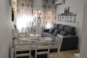 ein Wohnzimmer mit einem Tisch, Stühlen und einem Sofa in der Unterkunft LUISAHOUSE, en el corazón de Sevilla y Triana in Sevilla