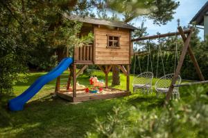 un parque infantil con una casa en el árbol y un tobogán en Brzozowy Zakątek, en Dziemiany