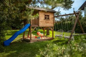 a playground with a tree house and a slide at Brzozowy Zakątek in Dziemiany