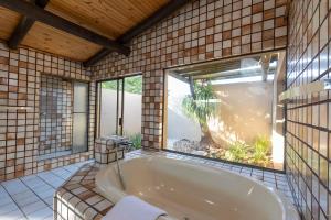 uma banheira num quarto com uma grande janela em The Pal Guest House em Gaborone