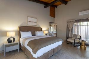 a bedroom with a large bed and a chair at The Pal Guest House in Gaborone