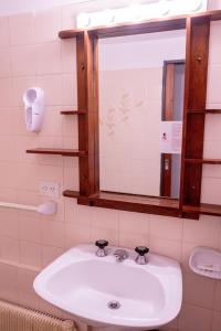 La salle de bains est pourvue d'un lavabo blanc et d'un miroir. dans l'établissement Hotel Centro SMANDES, à San Martín de los Andes