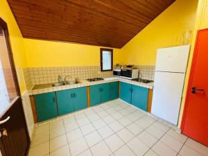 een keuken met blauwe kasten en een witte koelkast bij Gîte de Painfaut pour 12 personnes in Avessac