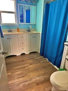 uma casa de banho com 2 lavatórios e uma cortina de chuveiro azul em Athena's Oceanfront Haven em Surfside Beach