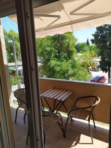 a porch with two chairs and a table and an umbrella at 100sqm comfort free parking Airport 10min in Thessaloniki
