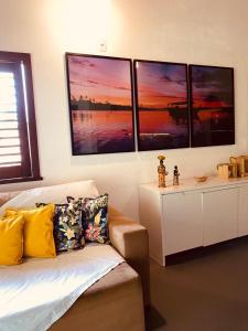 uma sala de estar com um sofá e quatro fotografias na parede em Casa Vida Li na Ilha de Boipeba