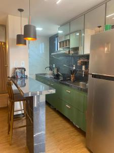 a kitchen with green cabinets and a stainless steel refrigerator at FLAT NA PRAIA DO MEIO in São-José-do-Ribamar