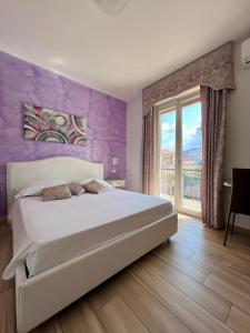 a bedroom with a white bed and a purple wall at Bella Tropea Accommodation in Tropea