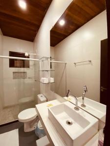 a white bathroom with a sink and a toilet at Casa Vida Li in Ilha de Boipeba