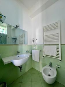 a green and white bathroom with a sink and a toilet at Bella Tropea Accommodation in Tropea