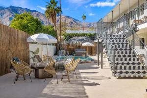 パーム・スプリングスにあるThe Maya - Entire Hotel Buyout - Private Gym - Private Game Room - Private Living Areaの山々を背景にテーブルと椅子が備わるパティオ
