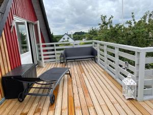 a deck with a bench and a chair on a house at Lejlighed med tagterrasse, have og pool. in Vipperød