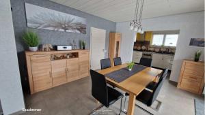 eine Küche mit einem Holztisch und schwarzen Stühlen in der Unterkunft Ferienhaus Guldner mit Terrasse, Garten und Sauna in Überherrn