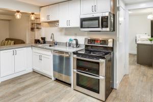 una cucina con elettrodomestici in acciaio inossidabile e armadietti bianchi di Steps to Idylwood Park Beach Redmond Retreat! a Redmond