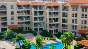 an aerial view of a building with a pool and palm trees at Good vibes, lovely sea and Breeze OASIS at Eagle Beach ARUBA in Palm-Eagle Beach