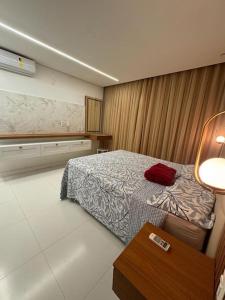 um quarto com uma cama e uma mesa com um candeeiro em Casa com 3 quartos e piscina - 8 min da Praia em São José de Ribamar