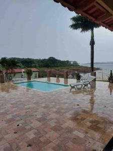 - une piscine avec 2 chaises et un palmier dans l'établissement Casa à beira lago de Furnas. (Pé na água), à Formiga